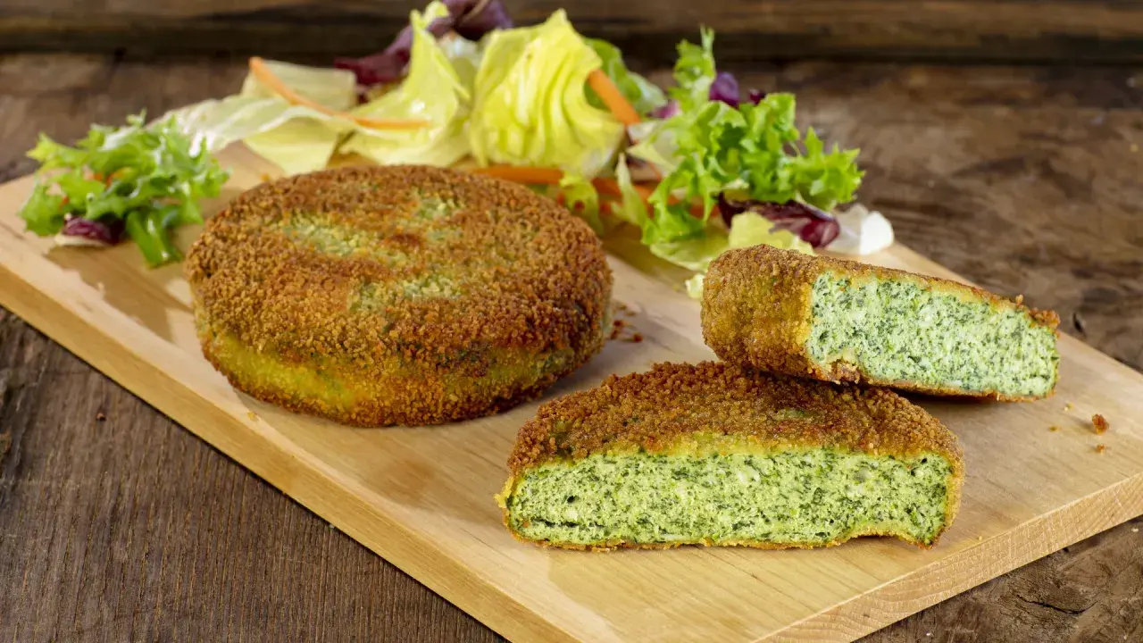 Deliziose spinacine fatte in casa, dorate e croccanti, servite con un'insalata fresca su un tagliere di legno.