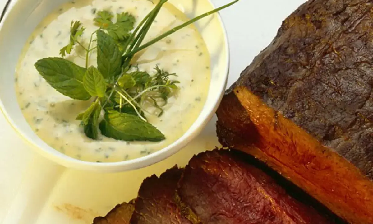 Sauce crémeuse aux herbes pour accompagner un rôti de bœuf juteux, garnie de menthe fraîche et de ciboulette.