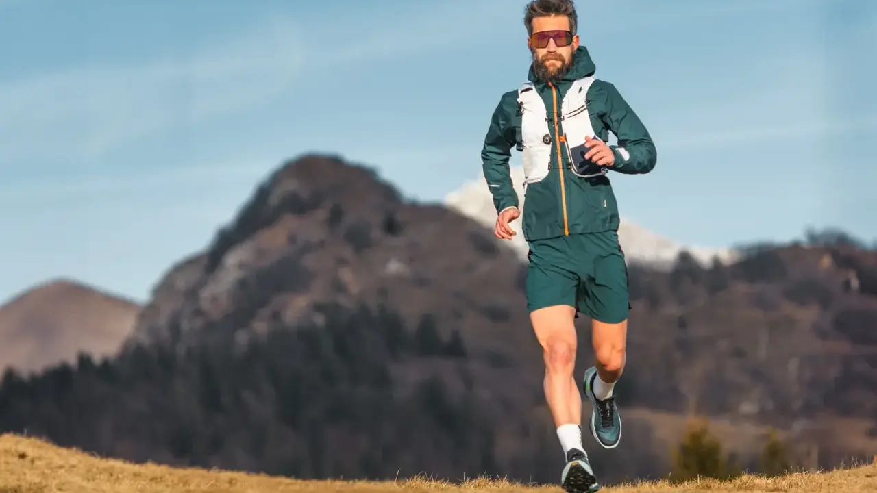 Ein Mann läuft in den Bergen, was ist ein ultramarathon? Er trägt Laufkleidung und eine Weste.