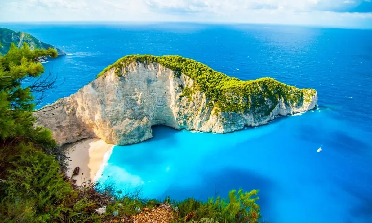 Widok na Navagio Beach, jedną z najpiękniejszych greckich atrakcji. Białe klify, turkusowa woda i zielona roślinność tworzą rajski krajobraz.