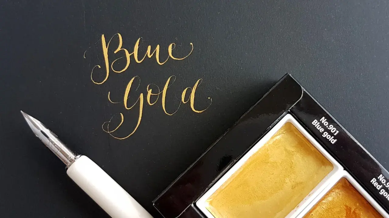 Złoty napis "Blue Gold" obok pióra i palety farb.