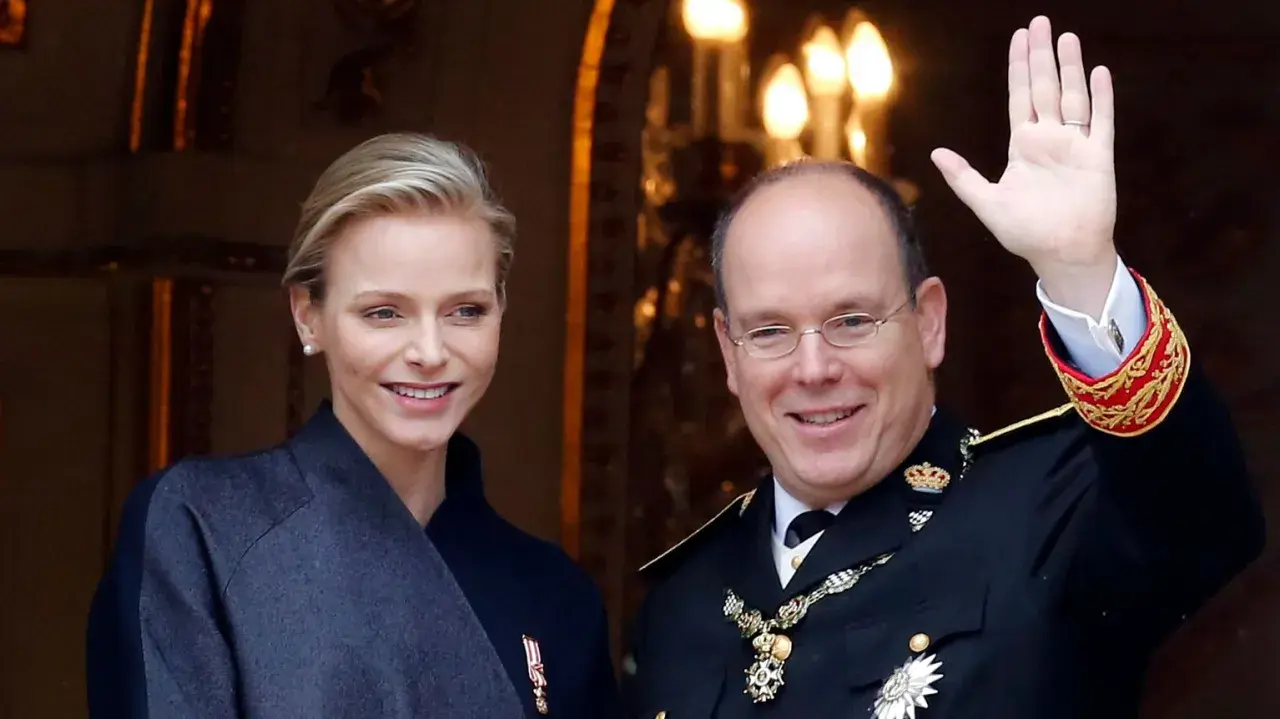 Charlene, furstinna av Monaco, ler vid sidan av prins Albert. Han vinkar glatt till publiken.