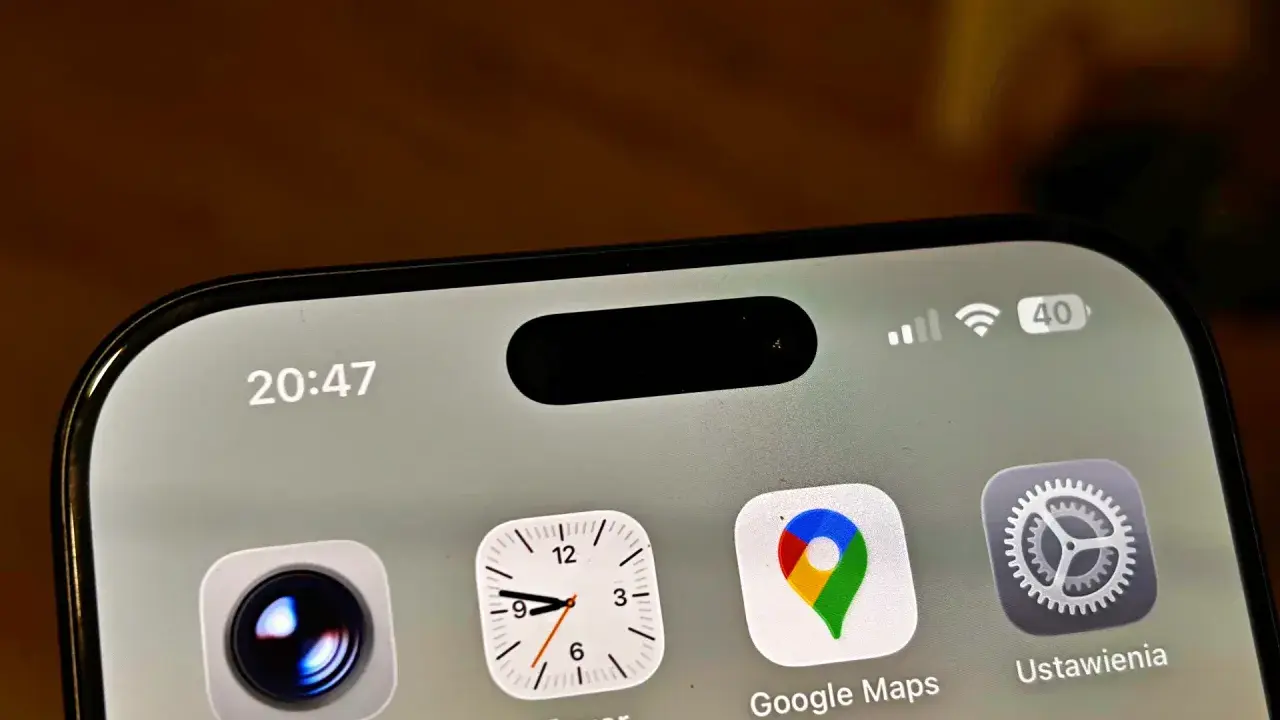 Ekran iPhone z widoczną dynamiczną wyspą, ikonami Aparat, Zegar, Google Maps i Ustawienia. Czas 20:47.