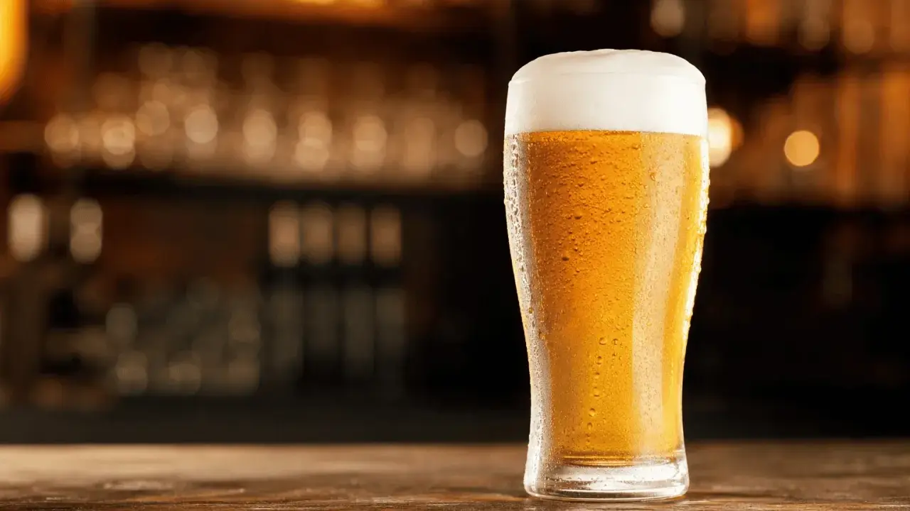 Schłodzony pilsner z obfitą pianką na blacie drewnianego baru.