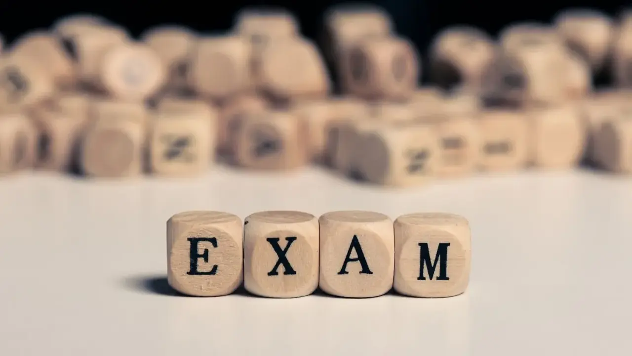 Drewniane kostki z literami tworzą napis "EXAM". Zastanawiasz się, na jakim poziomie jest matura podstawowa z angielskiego?
