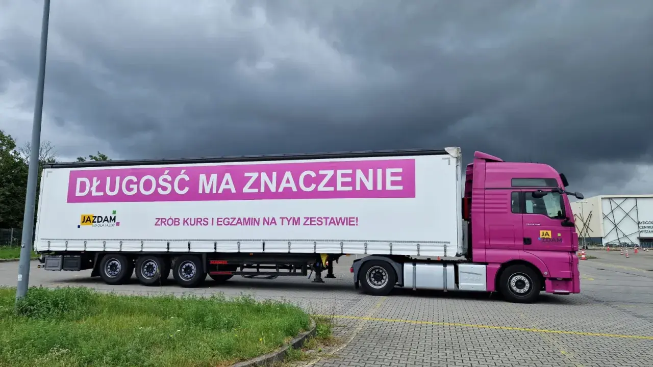 Różowa ciężarówka z napisem "Długość ma znaczenie. Zrób kurs i egzamin na tym zestawie!" zachęca do zdania egzaminu kwalifikacji zawodowej kierowcy.