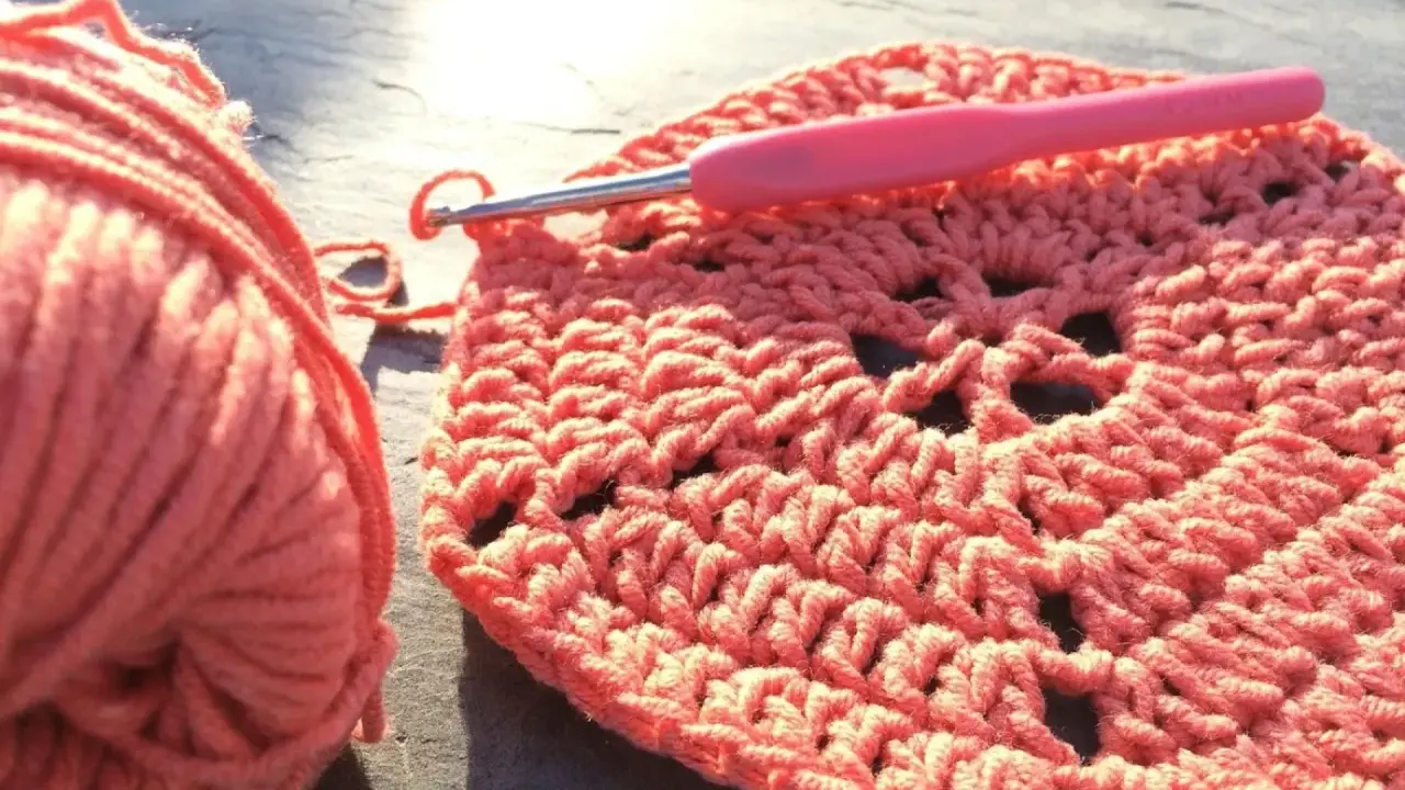 Koralowa włóczka i szydełko tworzą wzór. Powstaje piękny, ażurowy crochet pattern.