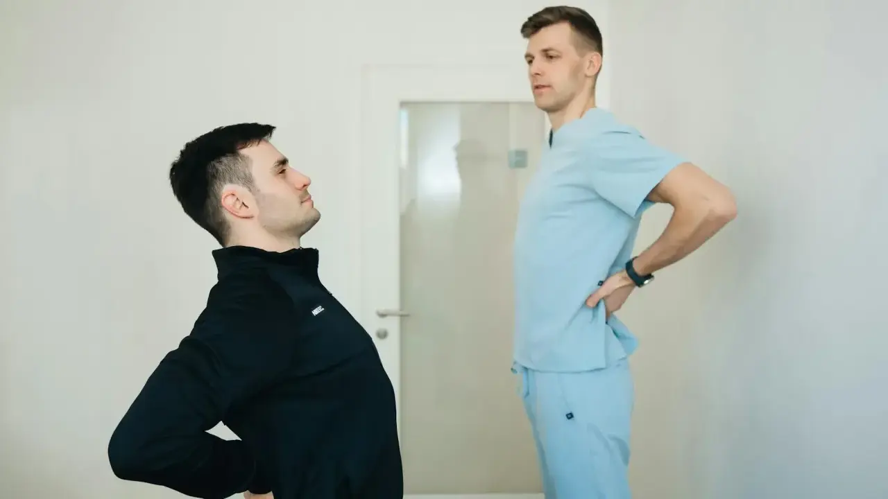 Fizjoterapeuta pomaga pacjentowi z chorobą Scheuermana w ćwiczeniach poprawiających postawę.