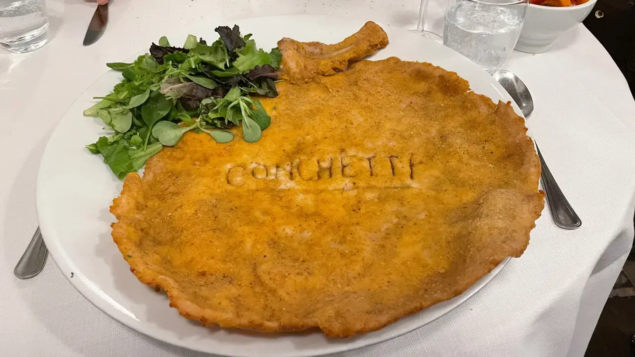 Cosa mangiare a Milano? Una cotoletta gigante con insalata fresca, un classico da provare assolutamente!