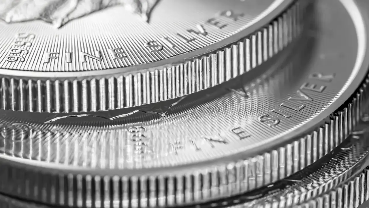 Zbliżenie na stos monet z napisem "FINE SILVER". Błyszczące srebro, idealne na prognozy inwestycyjne.