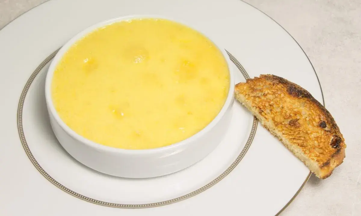 Crème onctueuse à la noix de coco, servie dans un bol blanc avec une tranche de pain grillé.