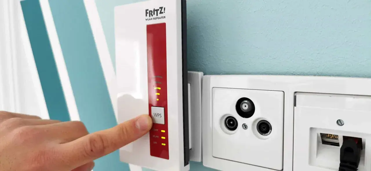 Fritz! WLAN Repeater verbessert das Signal, um **WLAN durch Betondecke** zu leiten. Ein Finger drückt auf die WPS-Taste.