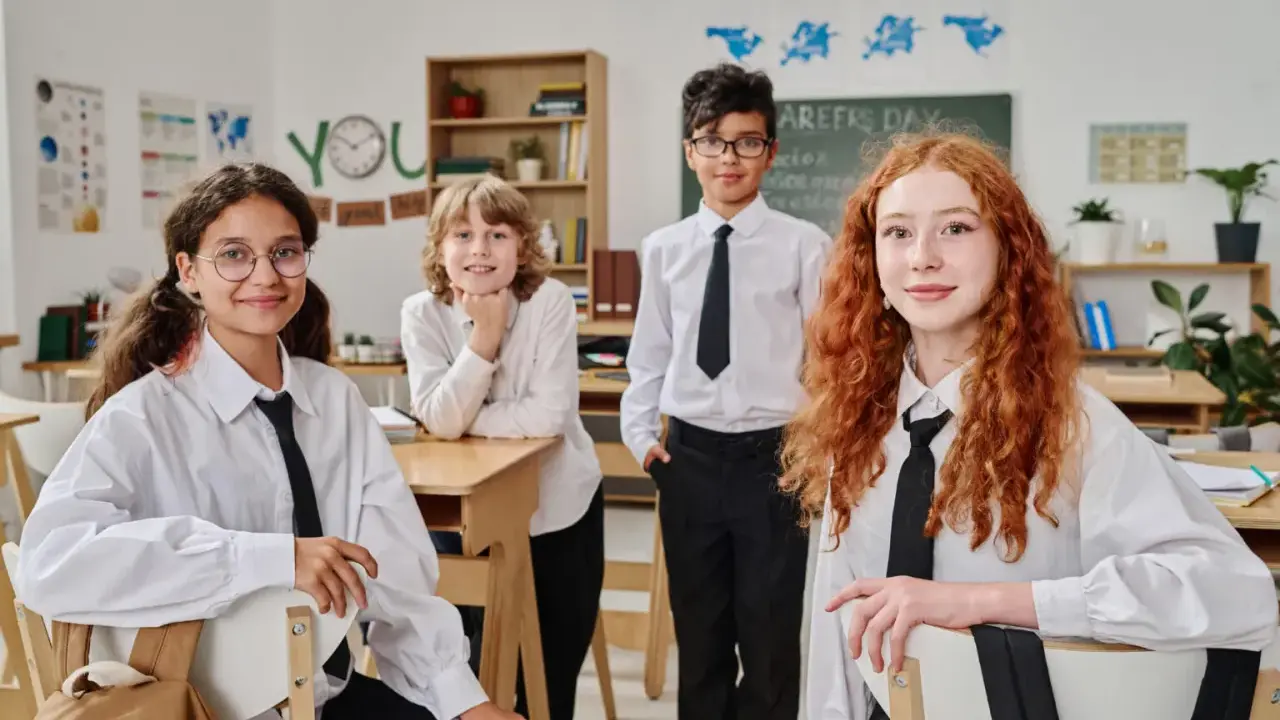 Vier Schüler in weißem Hemd und schwarzer Krawatte im Klassenzimmer. Ein Vergleich des Schulsystems Finnland und Deutschland könnte hier beginnen.