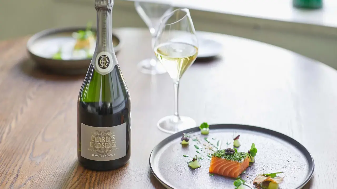 Flasche Charles Heidsieck Champagner neben Lachs mit Kaviar auf einem Teller.