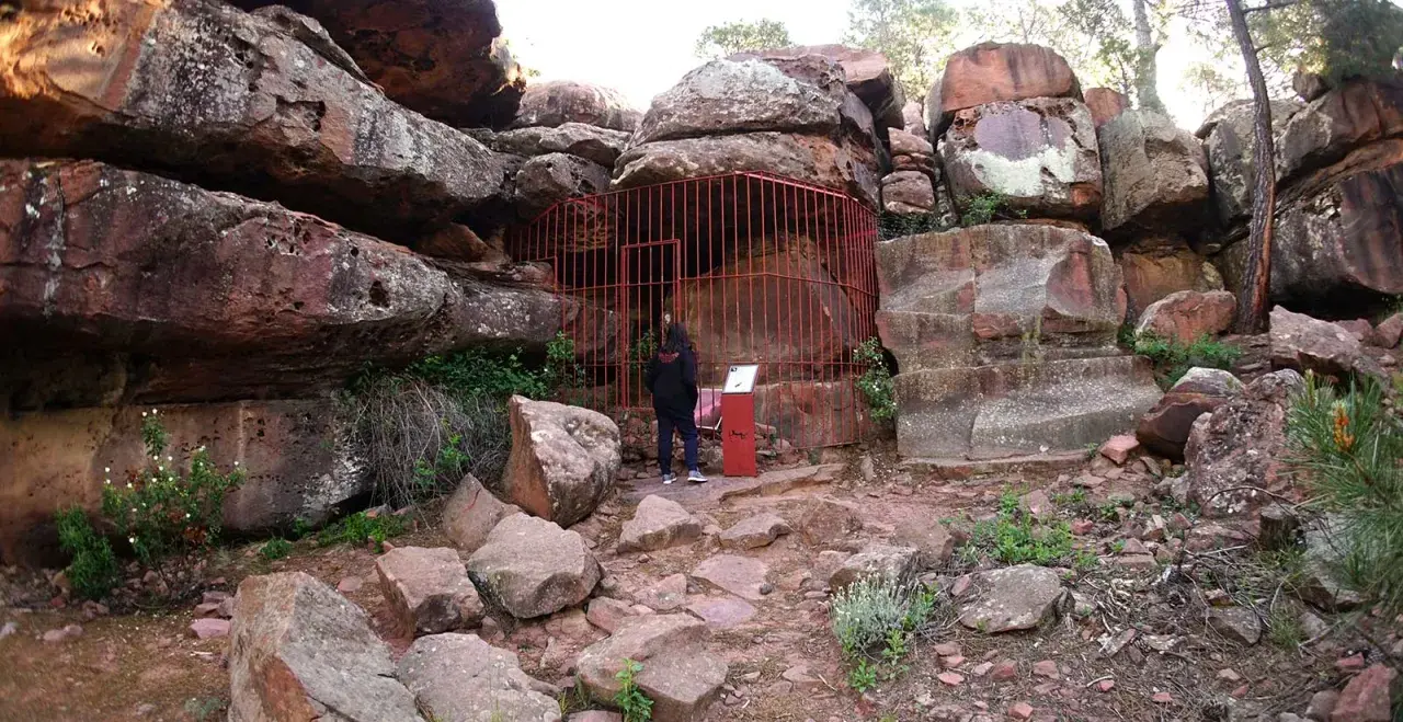 Persona observa pinturas rupestres albarracín, protegidas por una valla roja.