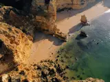 Malownicze klify i piaszczysta plaża w Portugalii. Morze o turkusowym odcieniu obmywa skaliste wybrzeże, tworząc idealne miejsce na spacer.