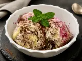 Schüssel mit Zuppa Inglese Gelato, garniert mit Minze und Schokoladenraspeln. Ein Löffel liegt daneben.
