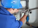 Instalator montuje odpowietrzenie kanału sanitarnego w domu parterowym.
