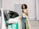 Frau mit Handy am Auto, bereit, einen Bolt anzurufen.