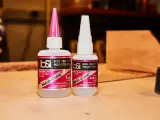 Two bottles of Bob Smith Industries Maxi-Cure glue, explaining why super glue is so strong due to its cyanoacrylate formula.