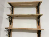 Scaffali fai da te garage: tre ripiani in legno grezzo, fissati a parete con staffe nere decorative. Perfetti per organizzare attrezzi e materiali.