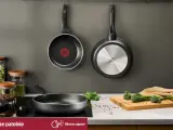 Dwie patelnie wiszące, jedna z logo Tefal, druga Gerlach. Na blacie patelnia, słoiki z makaronem i przyprawami, deska z brokułami. Czy patelnie Tefal można myć w zmywarce? Sprawdź!