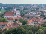 Widok na Wilno z wzgórza Giedymina. Czerwone dachy, białe kościoły i zielone drzewa tworzą malowniczy krajobraz.