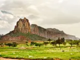 Etiopia: burzliwe niebo nad skalistymi górami i zieloną doliną z pasącym się bydłem. Pogoda zapowiada deszcz.