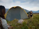 Mann und Frau biwakieren in Deutschland. Sie bauen ein Zelt in den Bergen auf, die Landschaft ist wunderschön.