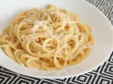 Pyszne spaghetti carbonara przepis na talerzu, posypane parmezanem i świeżo mielonym pieprzem.