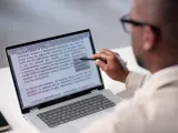 Un homme examine un document sur un écran d'ordinateur, soulignant des passages pour apprendre comment reconnaître une pièce fautée.