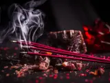 Varitas de incienso de sangre de dragón humeando, evocando su significado místico y protector.