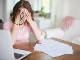 Kobieta z okularami w dłoniach, zamyka oczy, czując stres przed nową pracą. Na stole laptop i dokumenty.