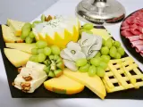 Plateau de fromage festif avec raisins verts, kiwi, noix et charcuterie. Une belle décoration plateau de fromage pour un événement.