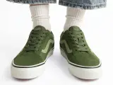 Zielone trampki Vans z jasną falą. Czy to rozmiar buta 11.5 cm? Białe skarpetki i podarte jeansy dopełniają stylizację.