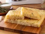 Focaccia senza glutine soffice e dorata, guarnita con rosmarino fresco, pronta per essere gustata.