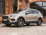 Beiger Seat Tarraco vor Backsteinhaus. Keine Seat Tarraco Probleme hier, nur stilvolles Fahren.