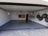 Nowa, lśniąca posadzka w garażu, cztery koła wiszące na ścianie, drabina i tablica narzędziowa.