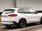 Białe BMW X5 M50d pędzi po autostradzie, zostawiając za sobą rozmyte tło.