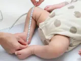 Dziecko w body w kropki, mierzone centymetrem. Sprawdzanie, jaki to rozmiar dla malucha do 3 miesięcy.