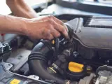 Ręce mechanika pracują przy silniku. Widoczny jest czarny przewód dolotowy i żółta zakrętka. p0101.