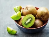 Miseczka pełna kiwi, jedno przekrojone na pół, pokazuje soczysty miąższ. Czy można jeść kiwi ze skórką? Tak, jest jadalna i pełna witamin!