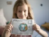 Uśmiechnięta dziewczynka pokazuje rysunek aparatu, przez który widać scenkę z pieskami. To świetna zabawa dla dziecka do lat 4 jak liczyć!