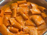 Rigatoni conditi con una cremosa salsa all'nduja, cosparsi di formaggio grattugiato. Un piatto invitante e saporito.