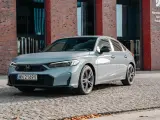 Nowoczesna, szara honda hybryda zaparkowana na bruku przed budynkiem Narodowej Orkiestry Symfonicznej Polskiego Radia.