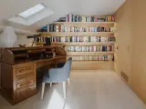 Scrivania in legno massiccio e libreria moderna illuminata, un perfetto esempio di come abbinare e mischiare arredamento classico e moderno in uno studio mansardato.