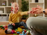 Chłopiec z nadwrażliwością sensoryczną bawi się plasteliną, jego dłoń wyciągnięta w stronę dłoni dorosłego.