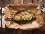 Gebackene Scholle mit Zitronenscheiben und Petersilie auf Backpapier. Perfekt zum Scholle essen!