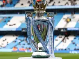Trofeum za mistrzostwo Anglii, błyszczące i ozdobione wstążkami Premier League, stoi na tle stadionu.