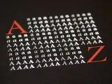 Duża czerwona litera "A" i rzędy białych liter "a" i "A" na czarnym tle, ilustrujące **kerning**. Obok czerwona litera "Z".